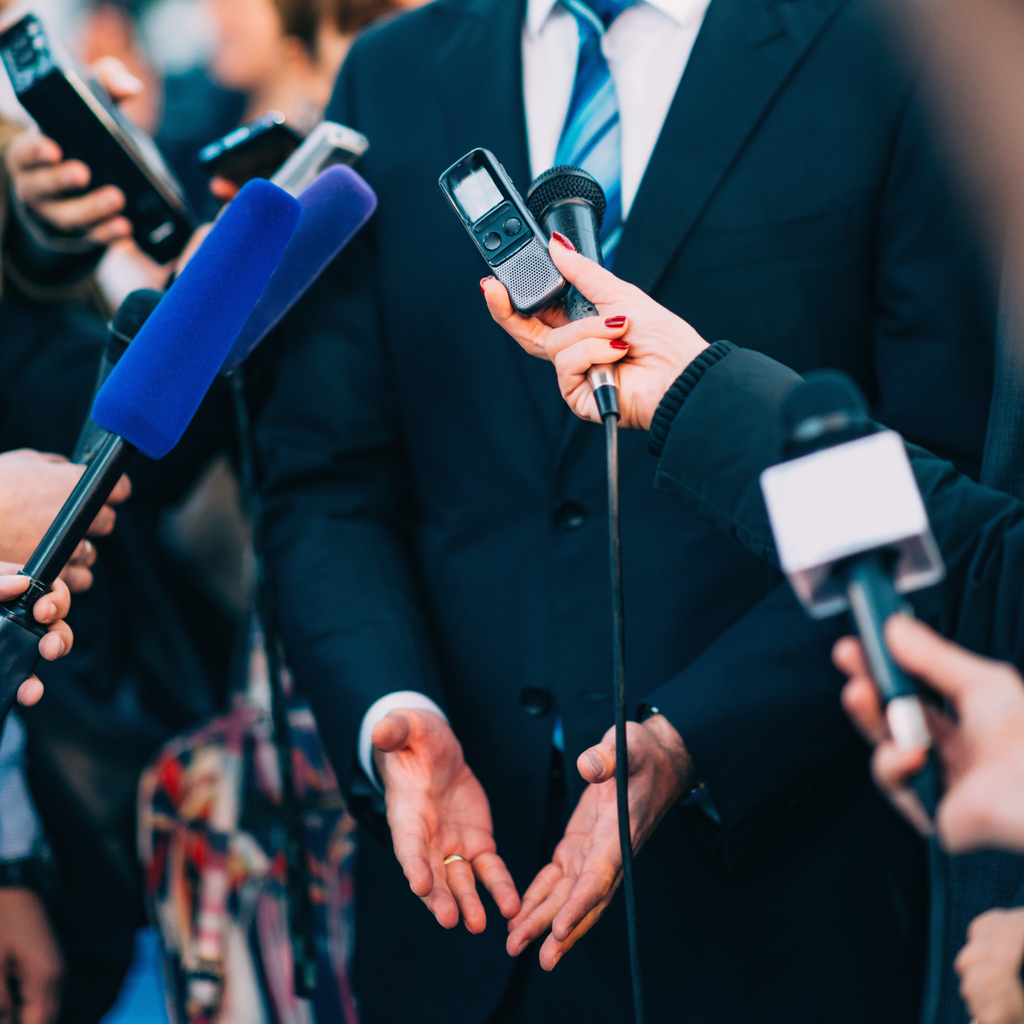 A businessman surrounded by microphones, tape recorders, and the news. Maintaining public trust is another reason why cyber security must support business intelligence.