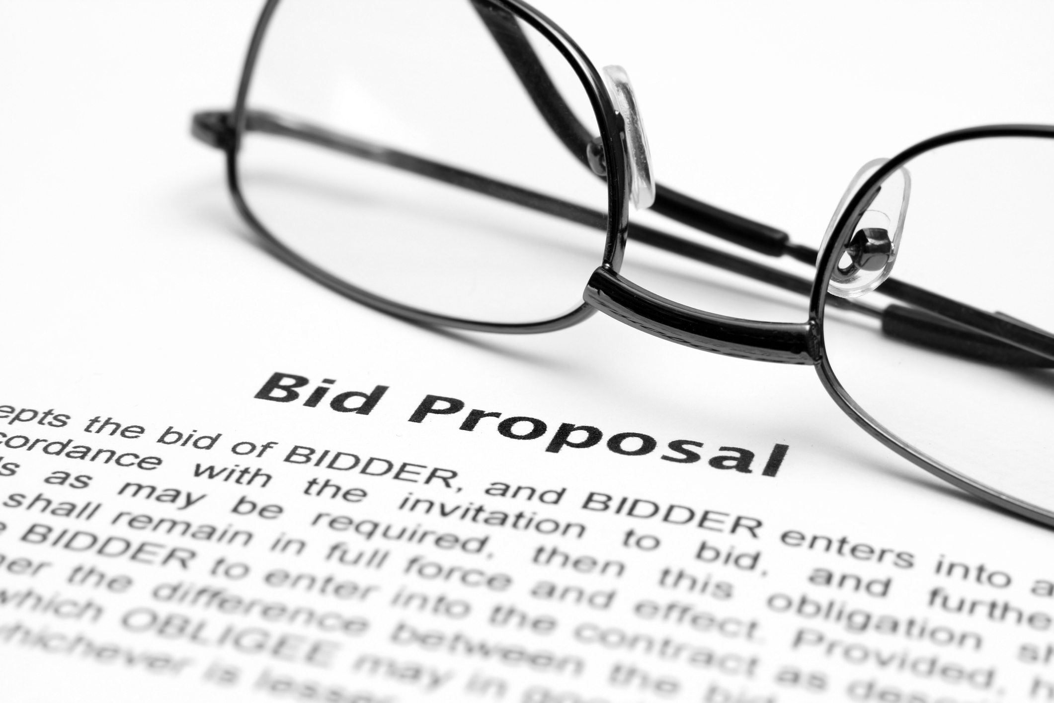 A bid proposal document with a pair of glasses laid on top.