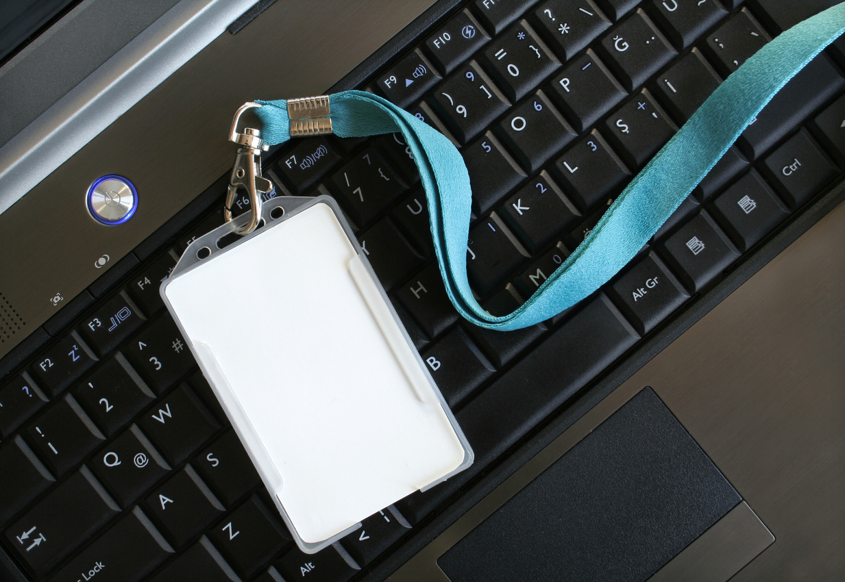 A lanyard with an identification card resting on a computer keyboard, representing a security clearance.