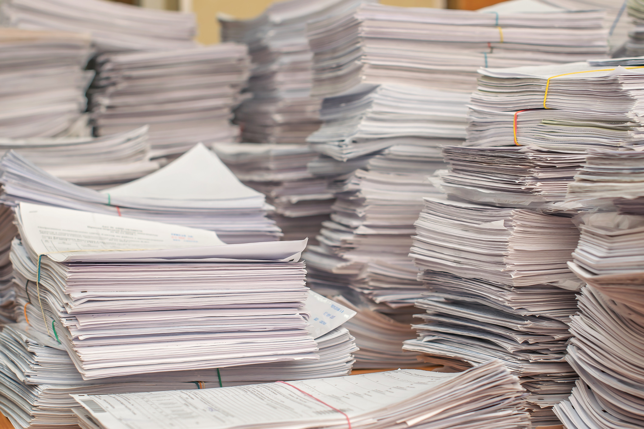 Huge piles of paperwork covering a desk, representing the security clearance backlog in 2019.