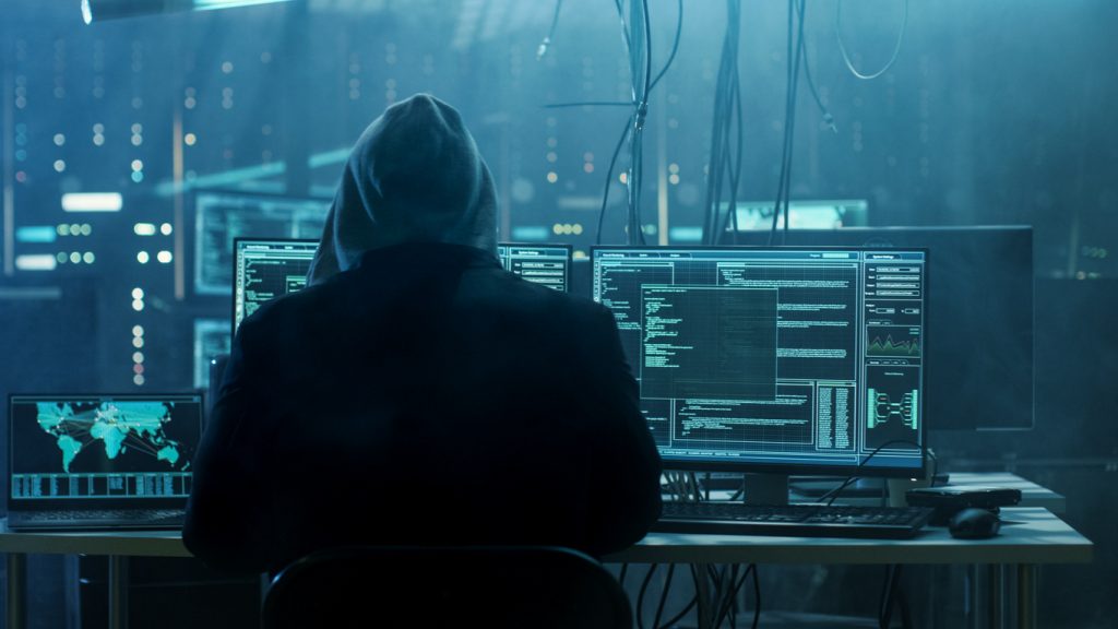 Cyber monitoring is a proactive technique against cybercriminals, like this hacker with their computer equipment.