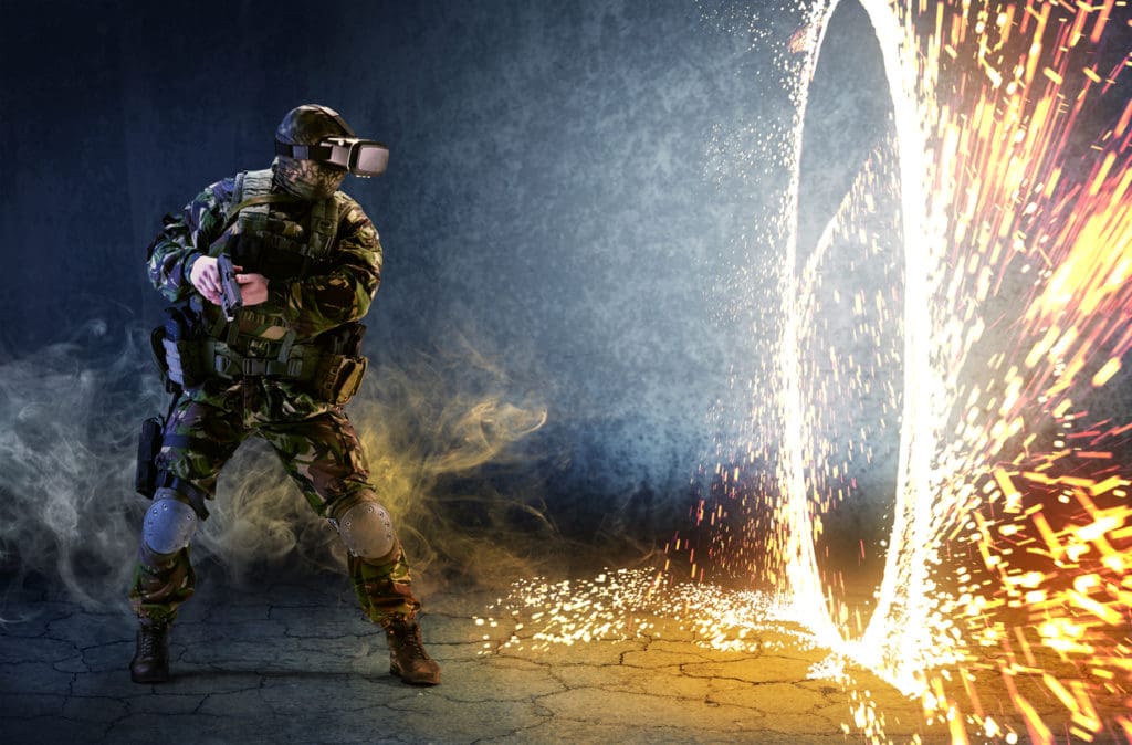 Servicemember in virtual reality suit interacts with virtual warfare environment.